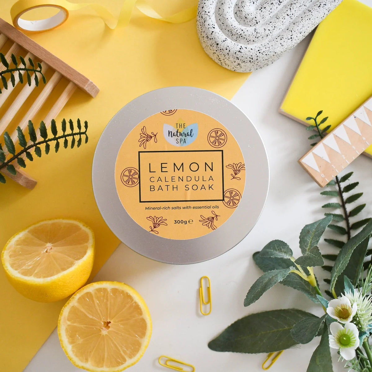 lemon calendula bath soak in an aluminium tin, placed on a yellow surface with decorative elements.