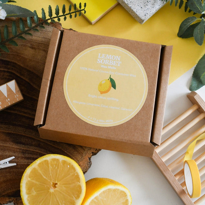lemon sorbet wax melts in gift box placed on a light surface with yellow accents and lemon slices