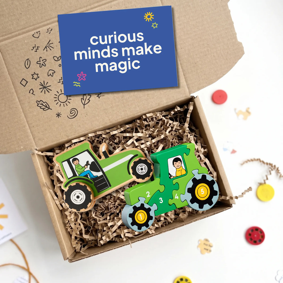 wooden push tractor and wooden 1-5 tractor puzzle in classic green. The toys are inside a kraft gift box with a card that reads 'curious minds make magic'