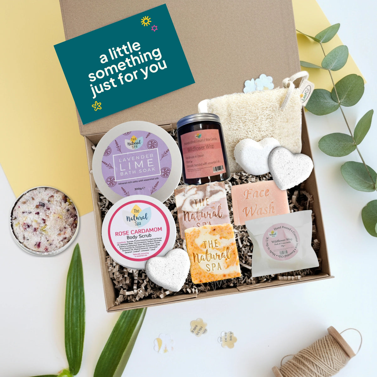 Gift box with natural self care products and a card reading 'a little something just for you' on a light background.