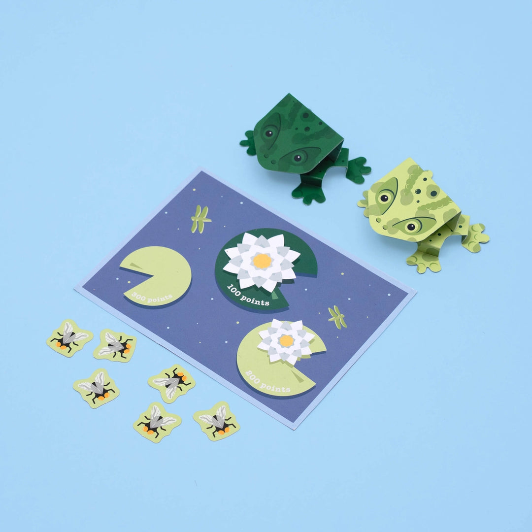 Paper craft set with frogs, lily pads, and flowers on a blue background