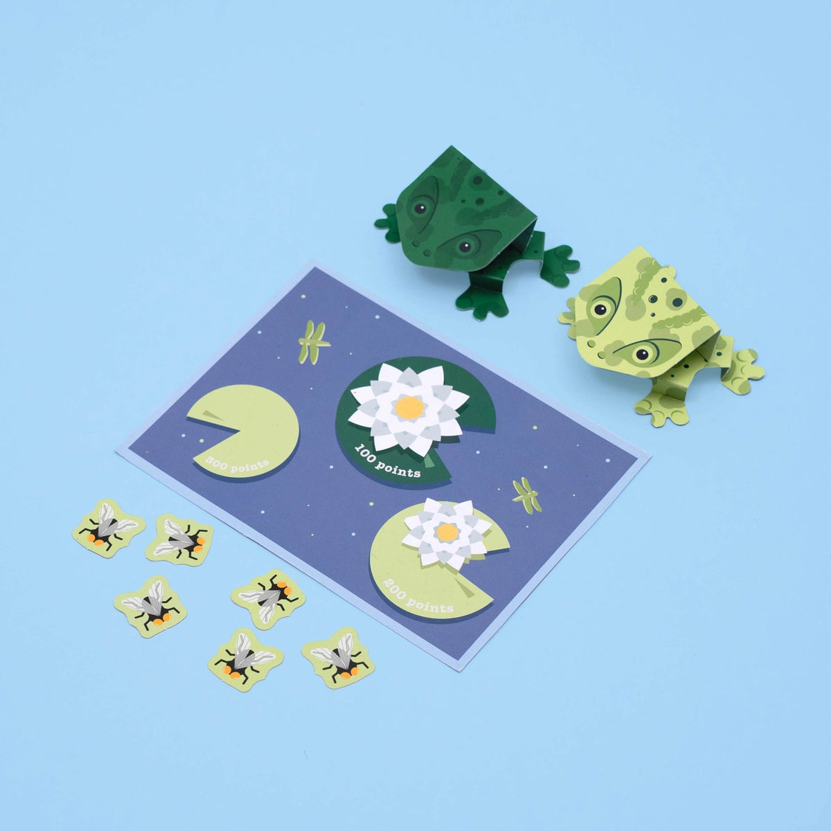 Paper craft set with frogs, lily pads, and flowers on a blue background