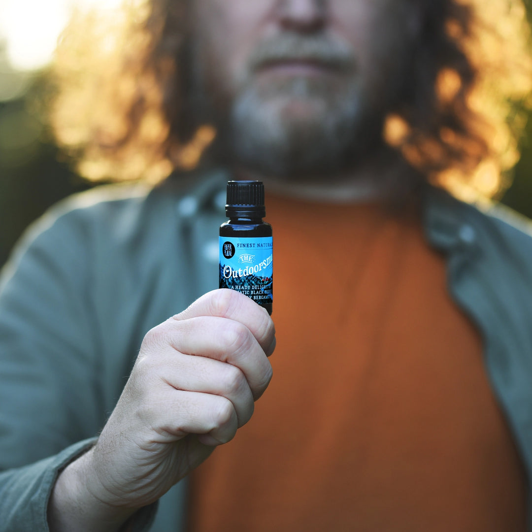 Person with beard holding a bottle of &