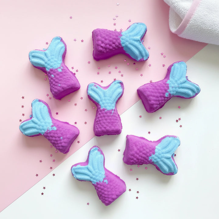 Purple and blue mermaid tail bath bomb for kids on a pink and white background