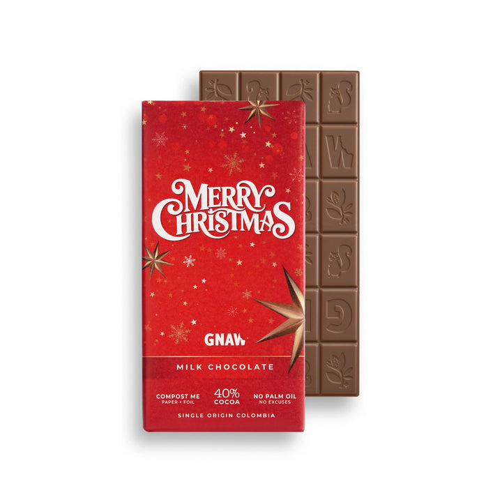 A GNAW brand Christmas-themed milk chocolate bar, showing the red wrapped packaging in front and the dark brown chocolate bar itself behind it on a white background.