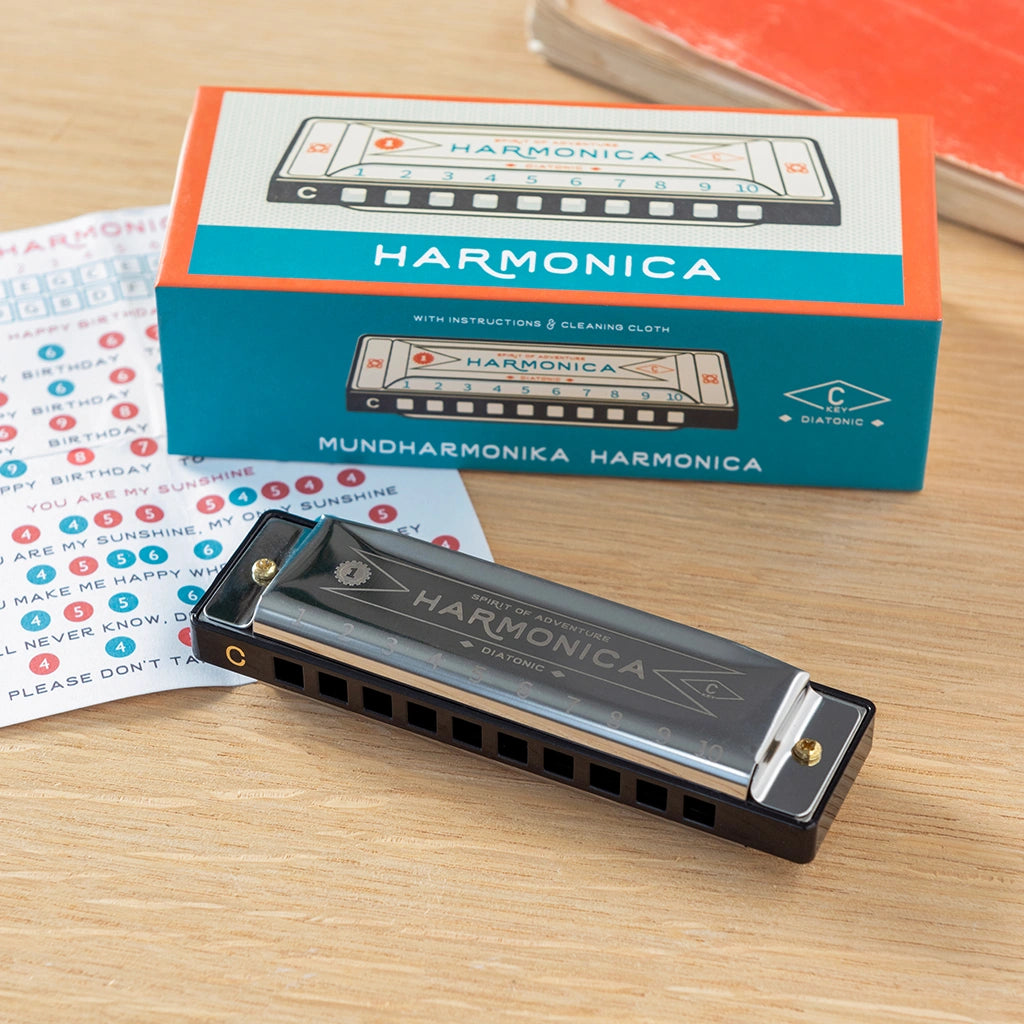 classic metal Harmonica with gift packaging , instructions and cleaning cloth on a wooden surface