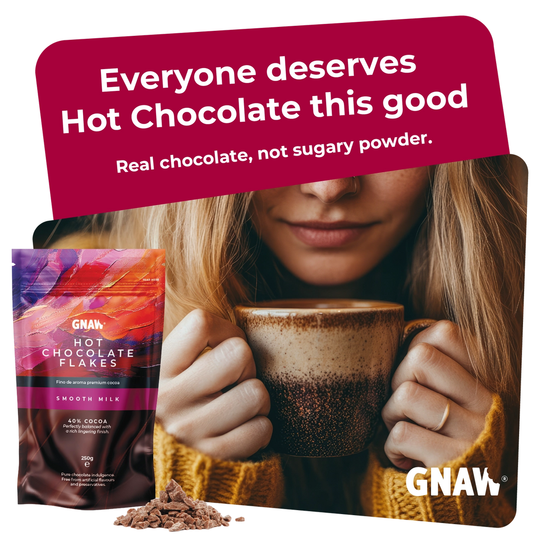 A promotional product image for GNAW Hot Chocolate Flakes. On the left is a stand-up pouch of Smooth Milk flavor hot chocolate flakes, with a small pile of the flakes in front.