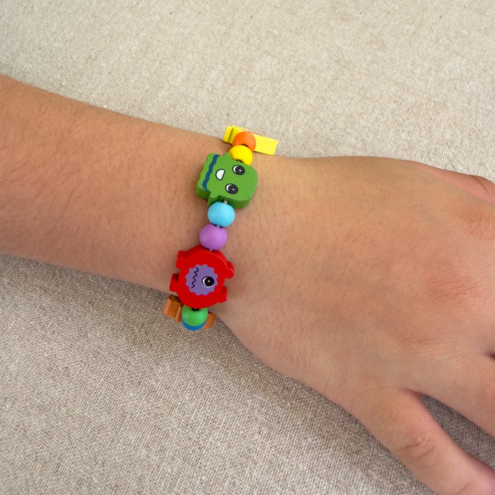 Colourful monster themed beaded bracelet on a wrist against a beige background