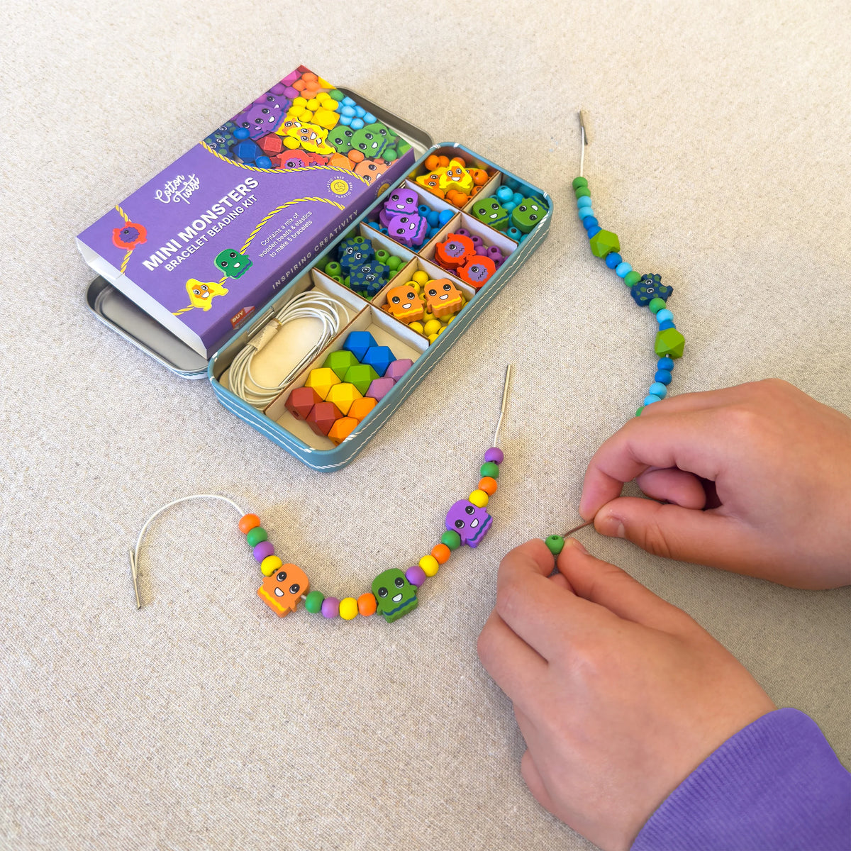 Colourful beaded necklace being made with a kit on a light surface