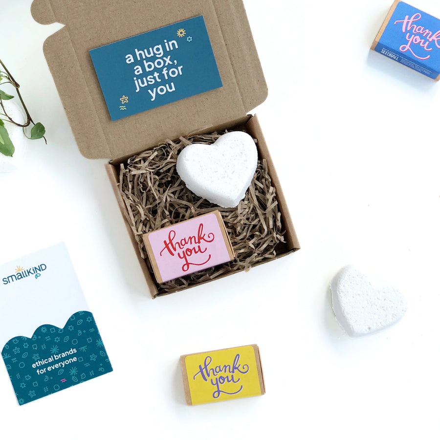 kraft gift box with a white bath bomb heart and a box of seedballs printed with a pink and red thank you message in looping text