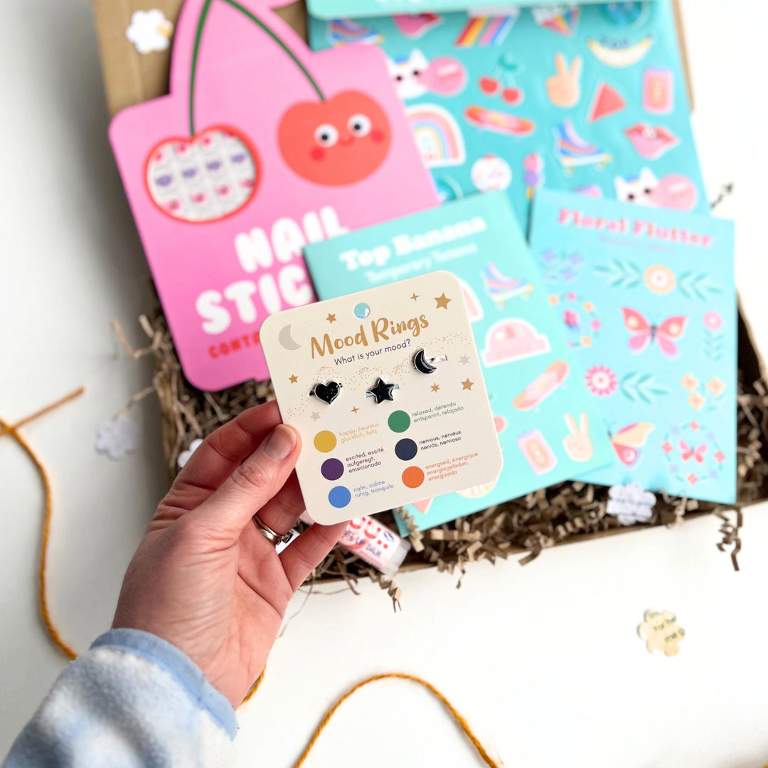 Hand holding a card with 'Meed Rings' product in front of Children's Nails + Beauty Gift