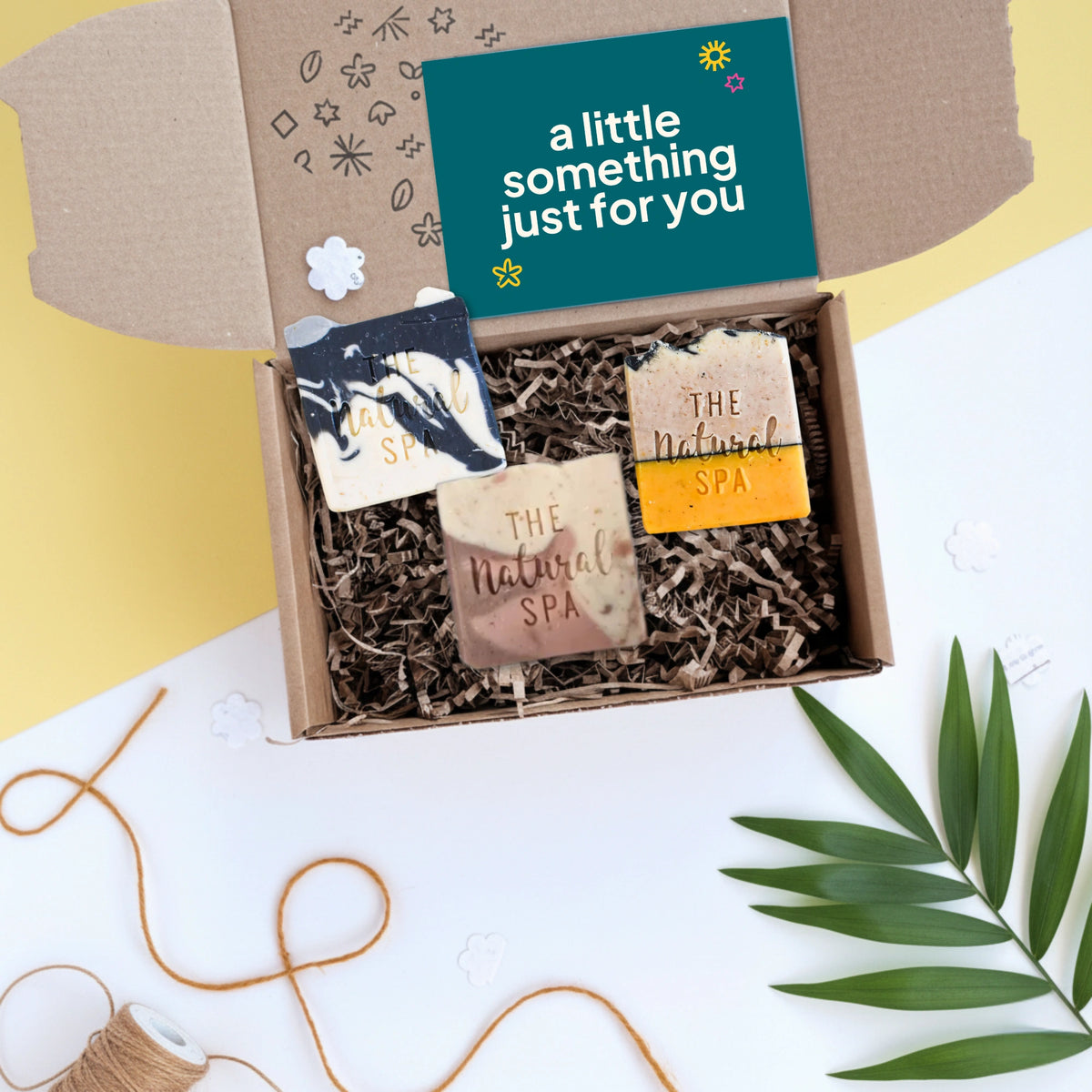 Gift box with three natural soap bars by 'The Natural Spa' and a card reading 'a little something just for you' on a white background.