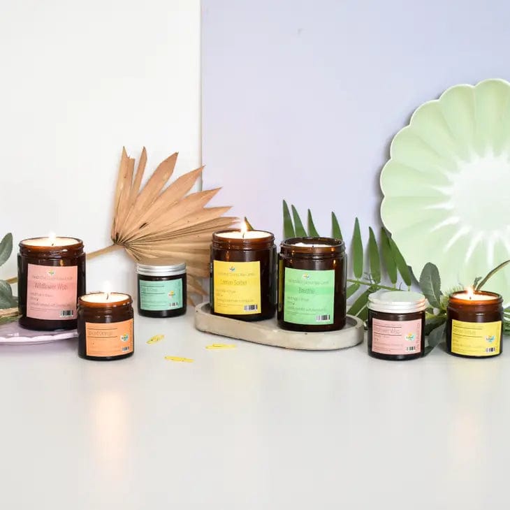 row of natural spa candles in amber glass jars with colourful labels