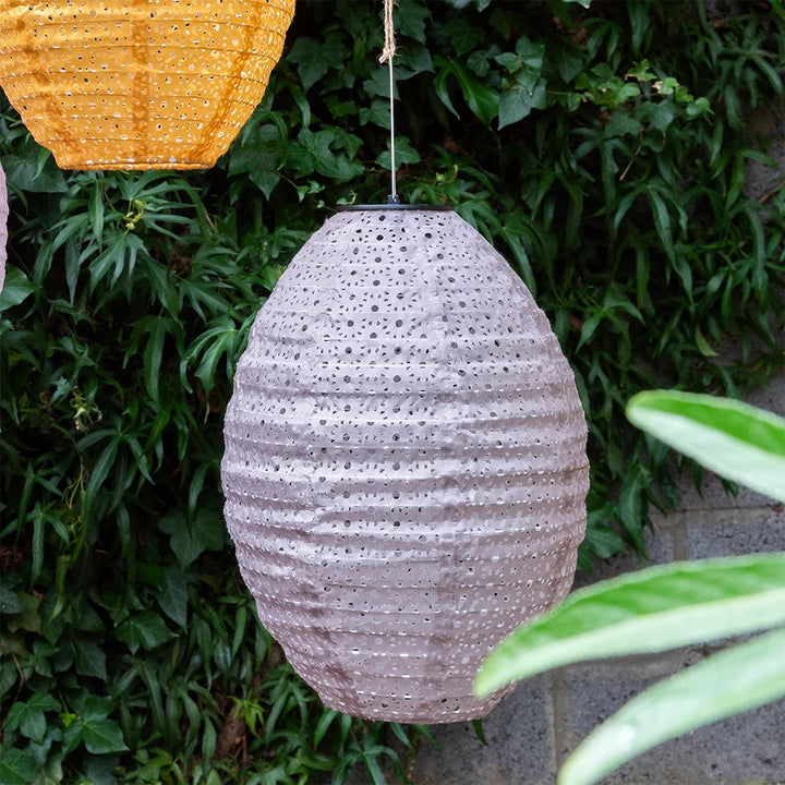 Textured hanging lamp against a green leafy background