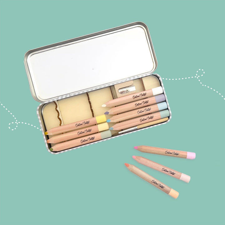 Set of chunky pastel coloured pencils in a metal case on a teal background