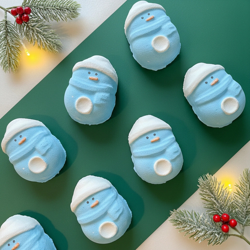 7 blue penguin bath bombs on a green background with festive holly branches