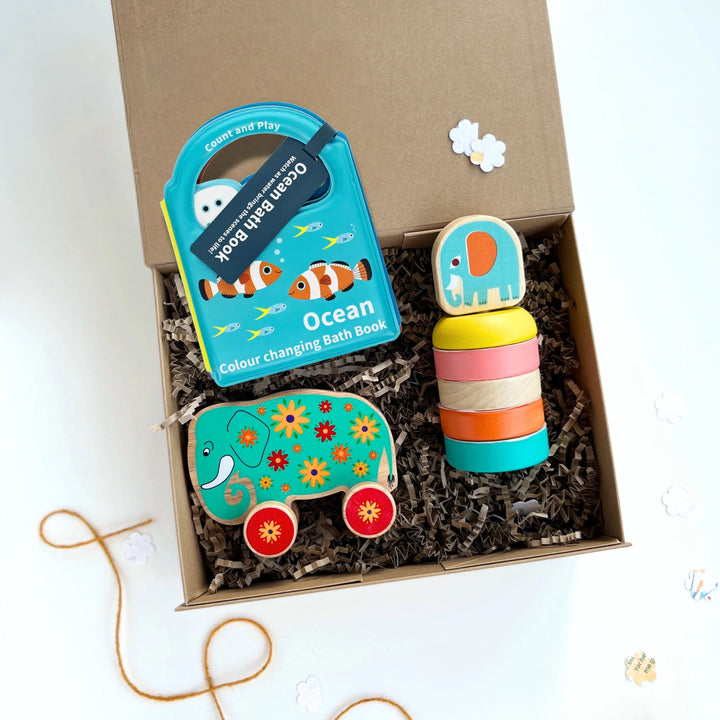 Colourful toys and a bath book in a luxury gift box on a white background