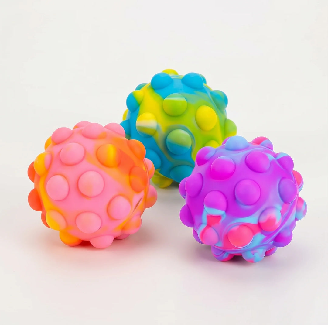 Three colourful textured sensory balls with raised circular bumps, shown on a clean white background. One ball is pink and orange, one is blue and yellow, and one is purple and pink.