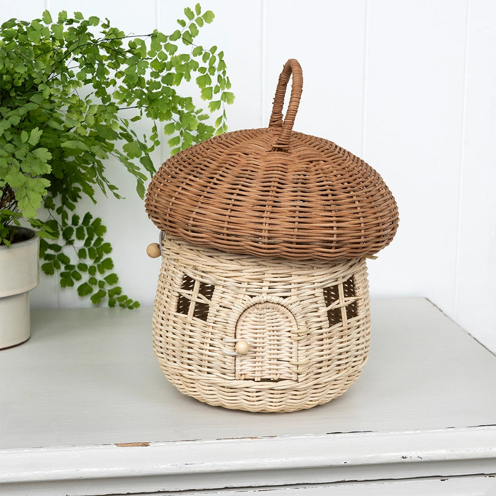 woodland inspired rattan mushroom house on a table with a a green leafy plant. perfect nature inspired home decor. 