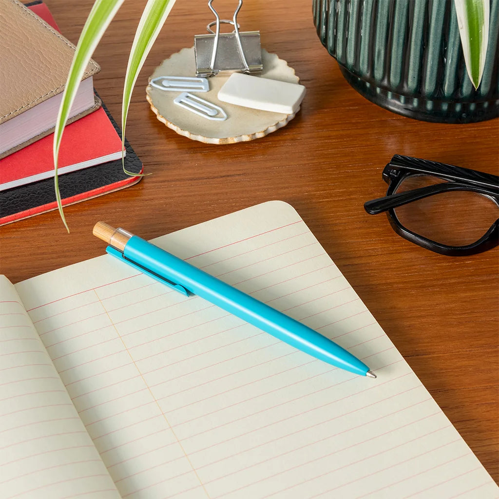 Blue pen on an open notebook with a wooden desk background