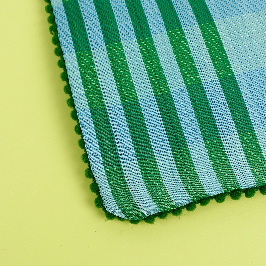 close up of a Respiin Recycled Woven Pom Pom Pouch in a blue and green checked design with a green pom pom trim