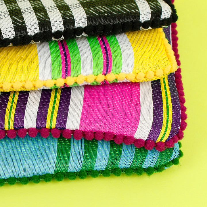 stack of blue, pink, yellow and black recycled colourful pouches with pom pom trims