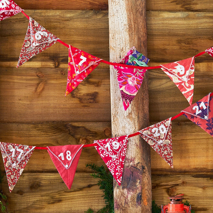 reusable Christmas Advent Calendar with red and white patterned triangular bunting with numbers hanging on a wooden post.