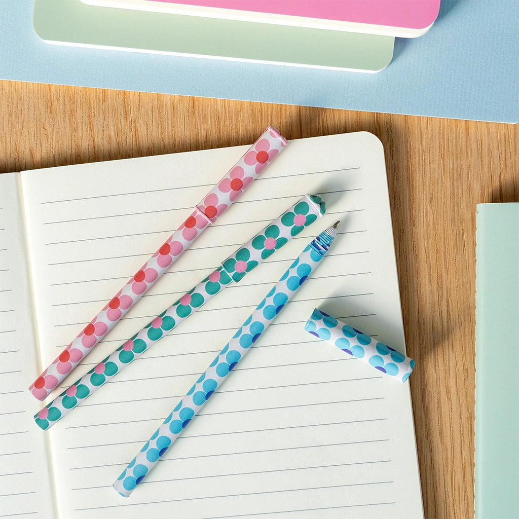 rex london daisy print paper pens in pink, blue and green on a wooden desk with pastel notebooks and stationery