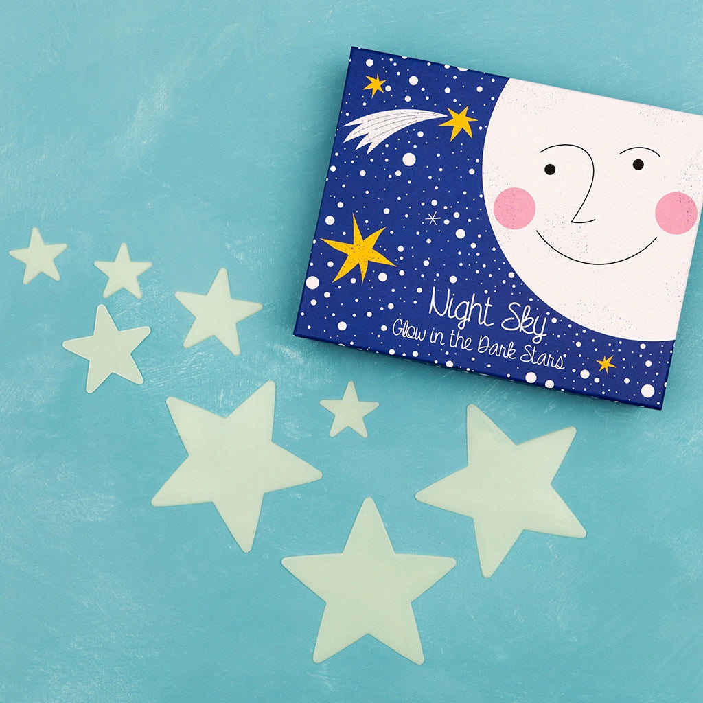 Glow in the Dark Stars by Rex London laid on a blue surface with a blue space themed gift box. 