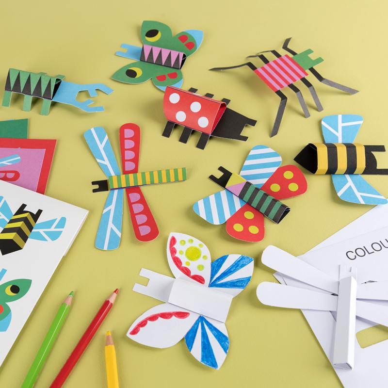 Finished bugs from the Make Your Own Cardboard Bugs Kit. The bugs are on a yellow table. 