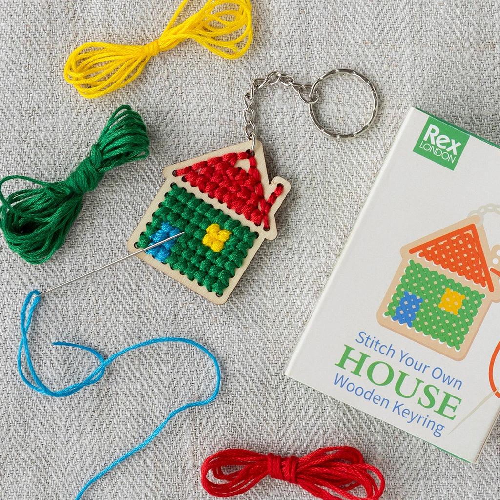 Stitch Your Own Wooden House Keyring by Rex London with a printed gift box. Easy beginner cross stitch kit laid on a linen table cloth