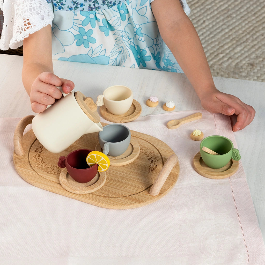 child playing with Rex London Wooden Toy Tea Set with colourful silicone cups, a white tea pot and wooden tray