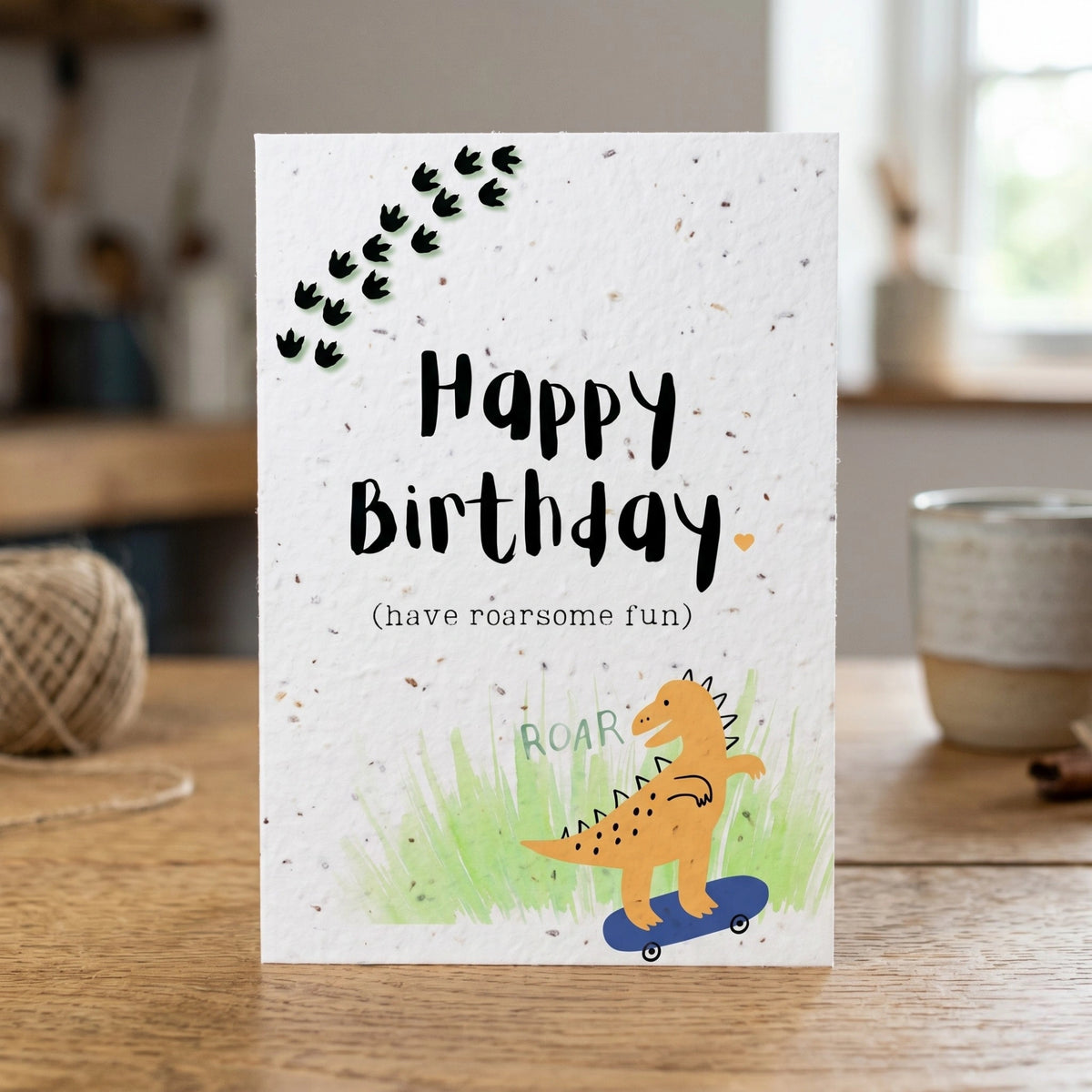 Birthday card with dinosaur illustration and 'Happy Birthday' text on a wooden surface.