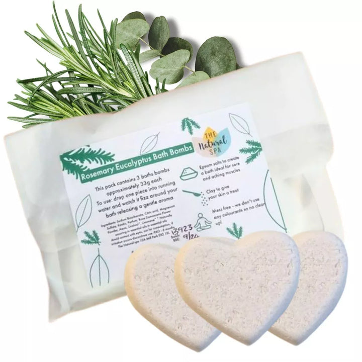 Packaged bath bombs  made by The Natural Spa with a label and rosemary leaves on a white background