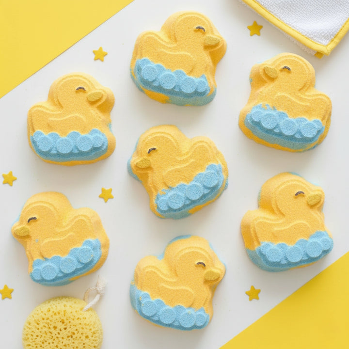 Yellow rubber ducky bath bombs with blue waves on a white background with yellow accents