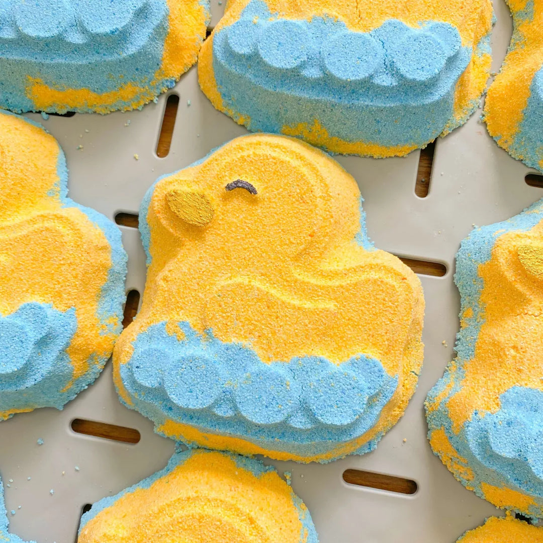 Yellow and blue duck-shaped bath bombs on a metal tray
