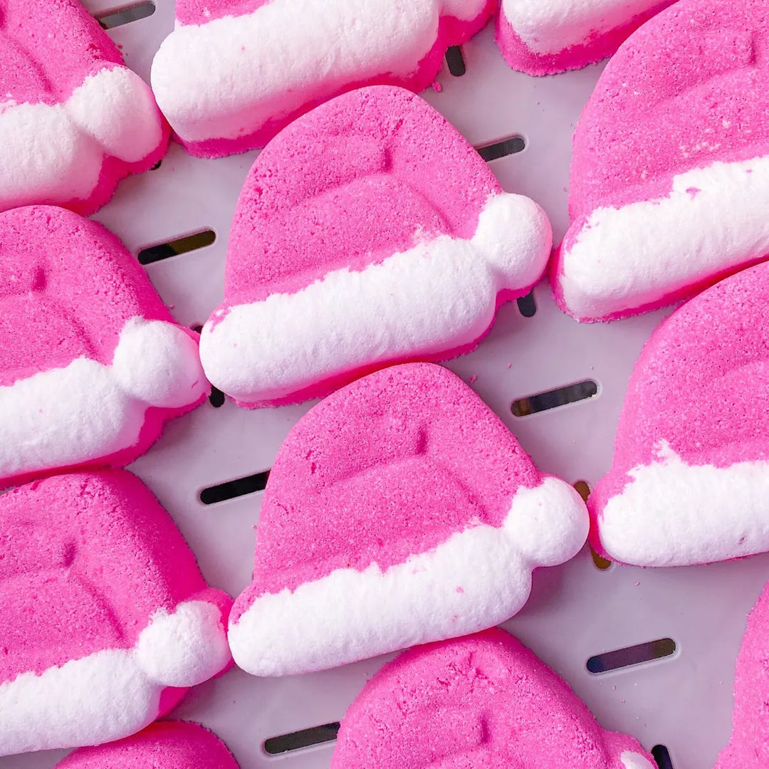 red bath bombs shaped like Santa hats on a white tray.