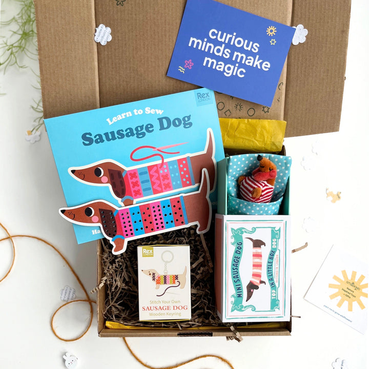 childrens craft gift box with 'Learn to Sew Sausage Dog', little sausage dog toy, sausage dog keying craft kit in a kraft gift box, featuring a 'curious minds make magic' card.