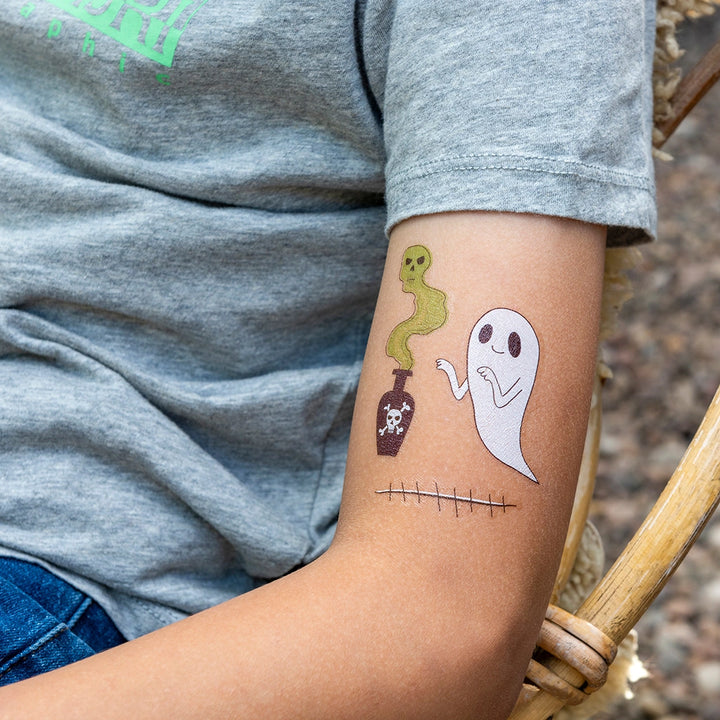 Temporary tattoos of a ghost, snake, and potion bottle on a person's arm.