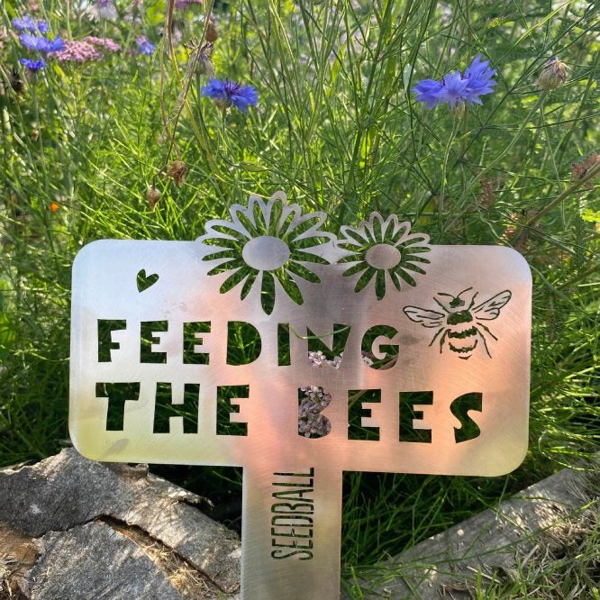 Feeding the Bees sign in a blooming wildflower patch - attract bees and support pollinators
