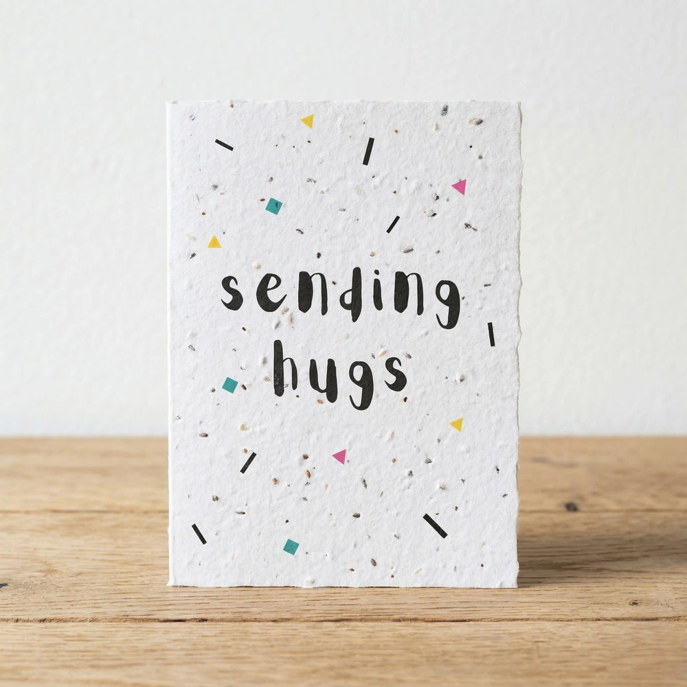 Card with 'sending hugs' text on a wooden surface