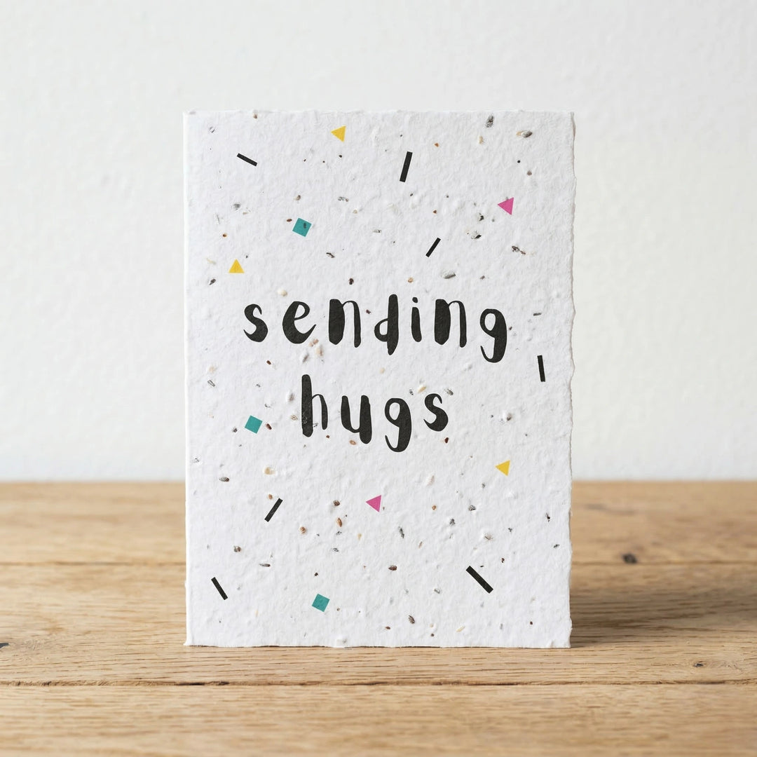 Card with 'sending hugs' text on a wooden surface