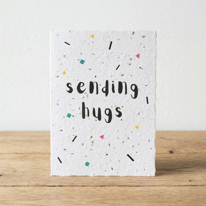 Card with 'sending hugs' text on a wooden surface