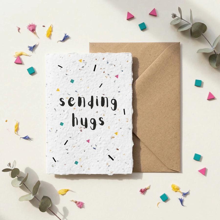 Greeting card with 'sending hugs' text on a white background with decorative elements.