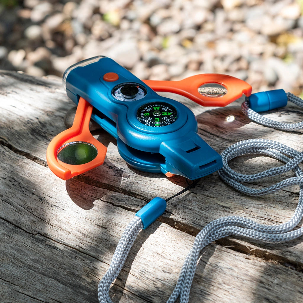 Multitool with compass and magnifying glass on a wooden surface outdoors