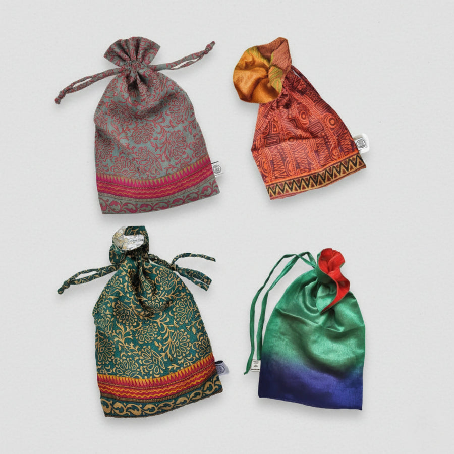Four colourful drawstring sari fabric gift bags on a light grey background