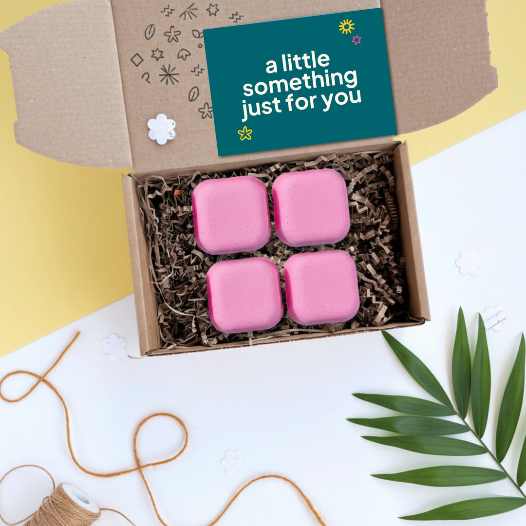 Shower steamer gift box with pink candy cane shower steamers and a card labeled 'a little something just for you' on a decorative background.