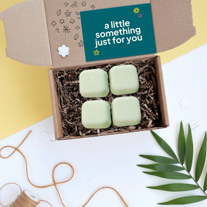 shower steamer gift box with green aromatherapy shower steamers and a card saying 'a little something just for you' on a white and yellow background.