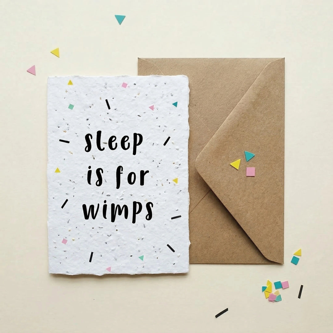 Greeting card with 'Sleep is for wimps' text on a white background with confetti, next to a brown envelope.