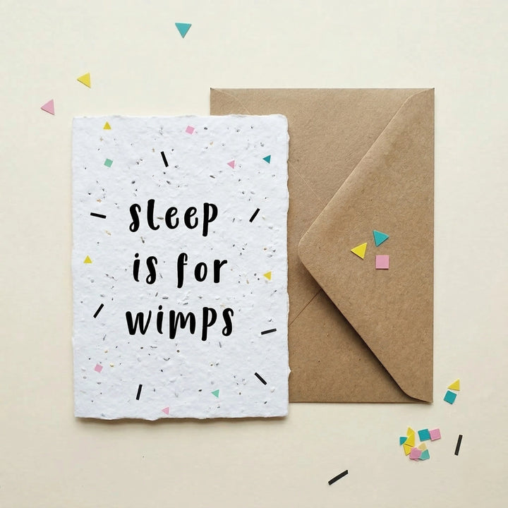 Greeting card with 'Sleep is for wimps' text on a white background with confetti, next to a brown envelope.